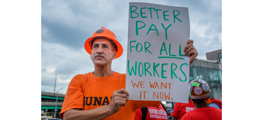 A construction worker holds a sign calling for higher wages.