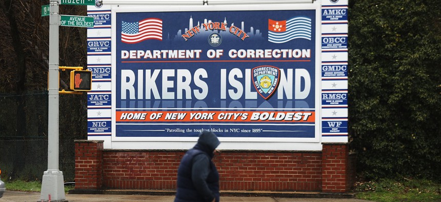 A person walks past a sign at the entrance to Rikers Island on March 31, 2017.