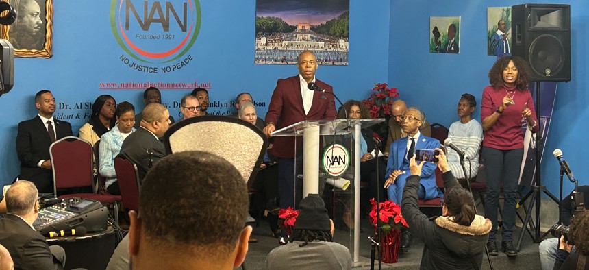 Mayor Eric Adams addresses the crowd at the Rev. Al Sharpton's Martin Luther King, Jr. Day event, while Sharpton looks on.