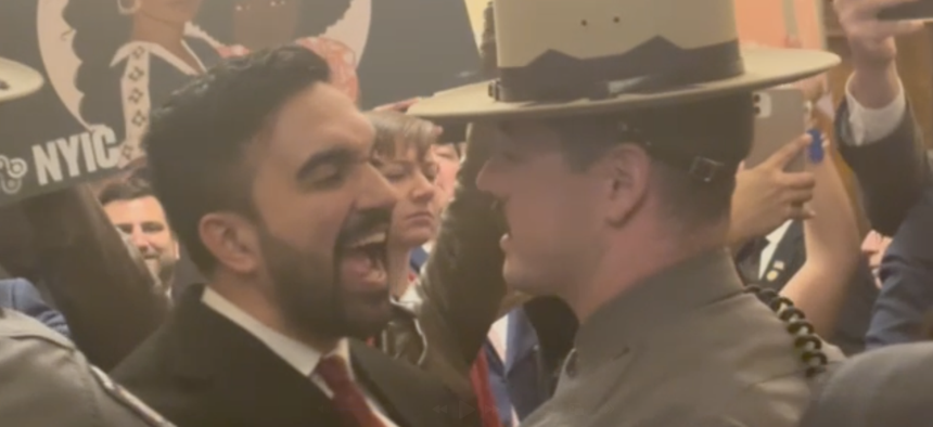 Assembly Member Zohran Mamdani, left, shouts questions at President Donald Trump’s border czar Tom Homan as state troopers hold him back, inside the state Capitol on March 12, 2025.