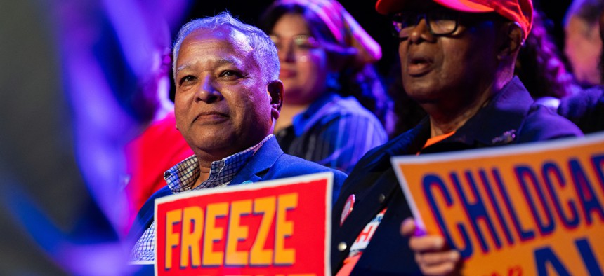 A supporter of Zohran Mamdani holds a sign with one of his signature promises on it at a rally in May.