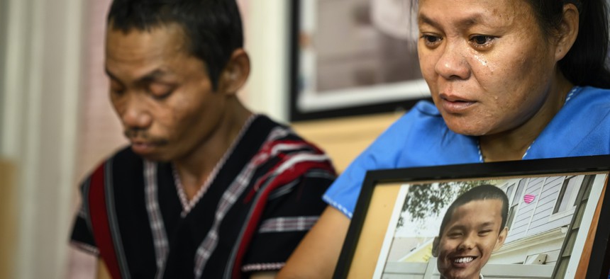 Chee War, mother of the late Nyah Mway, is overcome by emotion as she embraces his photo, with his father Ka Lee Wan on the left.