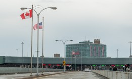 Flags wave at the Ontario New York border crossing. Canadian tourism has gone over a cliff.