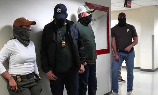 Masked ICE agents wait in the hallways outside immigration court at 26 Federal Plaza on Sept. 8, 2025.