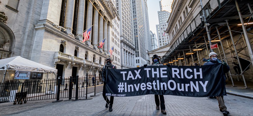 Demonstrators hold a “TAX THE RICH” banner outside the New York Stock Exchange on Jan. 28, 2021.