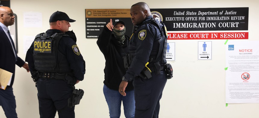 Federal immigration agents patrol the hallway outside immigration court at 26 Federal Plaza on Oct. 16, 2025.