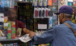 A man buys the New York Post and a Powerball ticket at a news stand in New York City on July 19, 2023.
