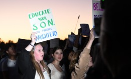 Demonstrators holds signs at a Women’s March protest on Oct. 8, 2026. 